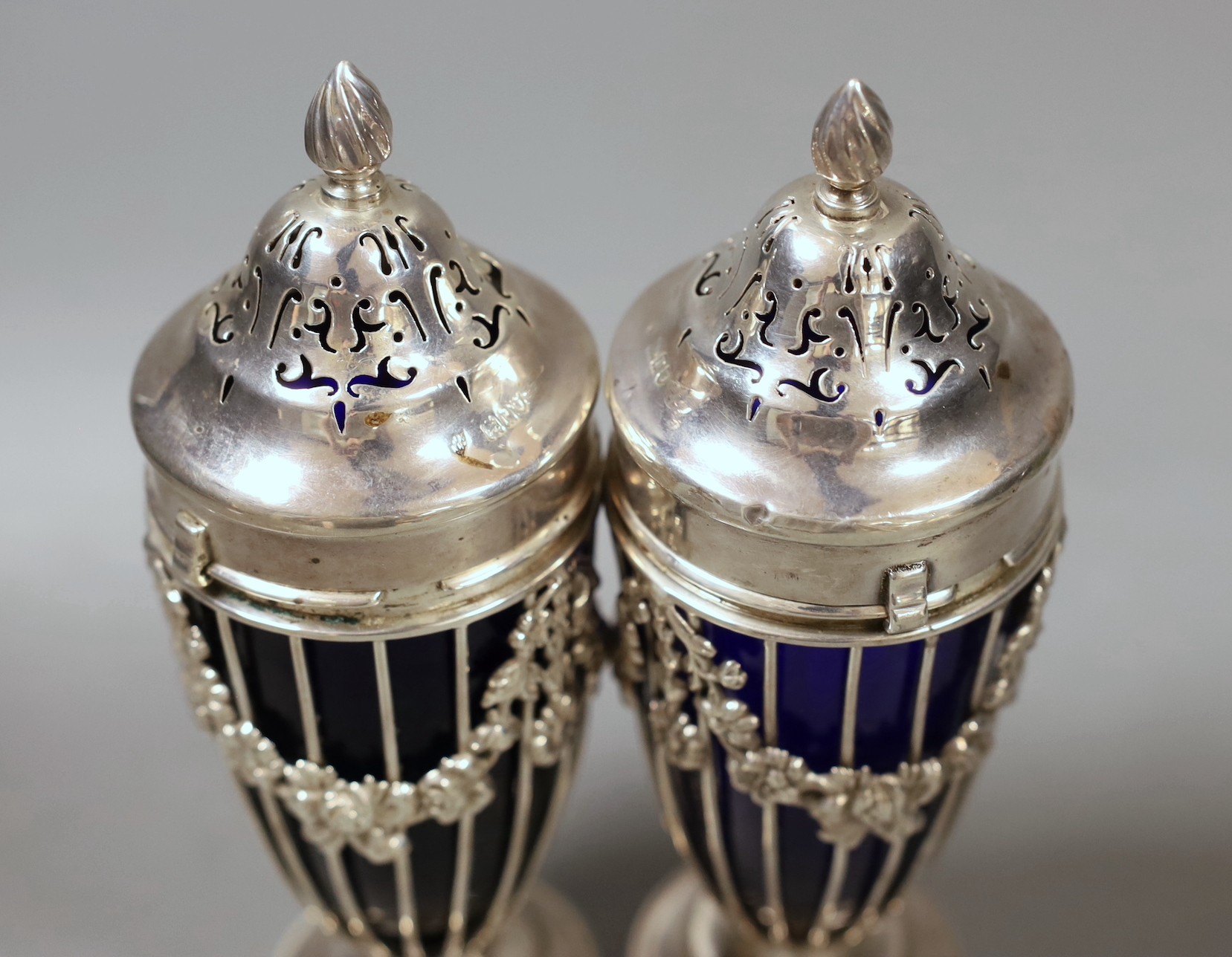 A pair of George V pierced silver sugar sifters, with blue glass liners, London, 1912, height 17.9cm.